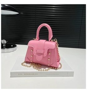 Dettaglio della borsa rosa in pelle PU con borchie dorate e tracolla a catena a sfere