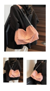 Detail of soft pink faux leather shoulder bag with silver chain strap on black suit