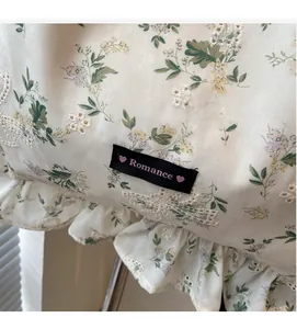 Détail du sac cabas floral en toile avec bordures à volants, broderie et étiquette