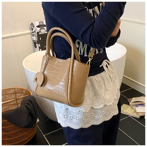 Detail of khaki crocodile pattern bucket bag with elephant charm and metal buckle strap