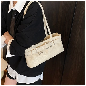 Close-up of cream leather shoulder bag with pebble texture and metallic buckle detail