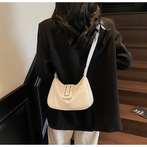Détail du sac demi-lune blanc crème avec boucle argentée sur un blazer noir chic