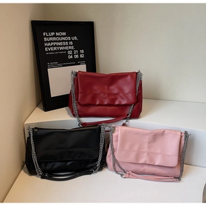 Detailed view of quilted faux leather shoulder bags in red, black, and pink with chain straps
