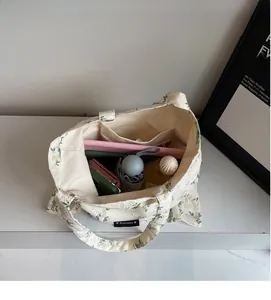 Détail de l'intérieur spacieux d'un sac cabas en toile fleurie avec divers objets