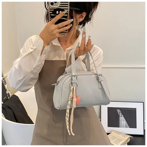 Détail d'un sac à main bleu clair en cuir verni avec breloque coeur rose et ruban