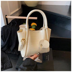 Detail showing beige crocodile-embossed leather tote with elephant charm and gold hardware