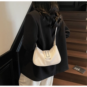 Sac sous le bras en cuir blanc avec boucle en métal argenté porté par un mannequin en costume