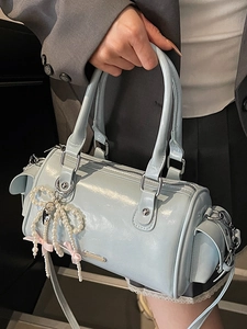 Light blue glossy Boston bag with pearl bow charm and pink ribbon on a gray blazer