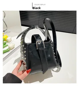 Détail du sac seau noir en cuir verni brillant avec des rivets argentés sur le côté