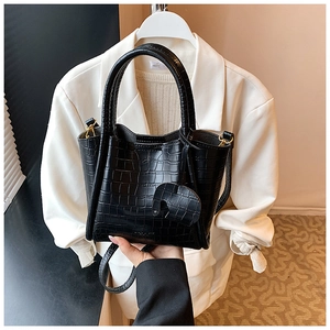 Close-up of black crocodile-textured tote bag featuring a cute elephant charm and gold hardware