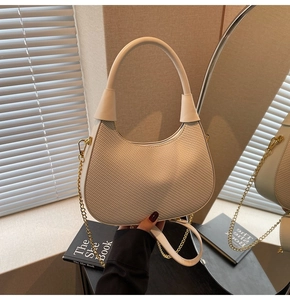 Detail der cremefarbenen geflochtenen Tasche mit Goldkette und Lederhandgriff