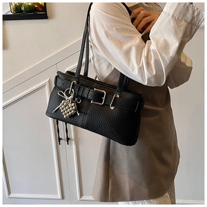 Chic black faux leather shoulder bag with silver buckle and heart charm on a model
