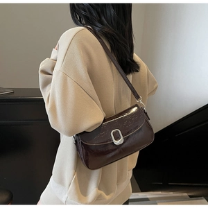 Detail view of dark brown glossy patent leather shoulder bag with vintage silver buckle