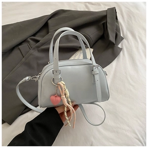 Gros plan d'un sac Boston bleu clair en cuir avec breloque cœur sur blazer gris