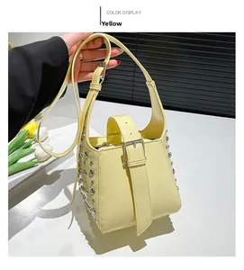 Détail du sac seau en cuir verni jaune avec clous argentés et fermoir métallique