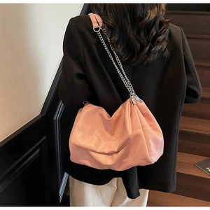 Detail of pink quilted leather underarm bag with silver chain strap worn by a model