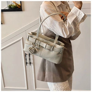 Detail of light grey leather shoulder bag featuring heart pearl charm and silver buckle