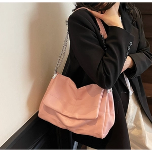 Close-up of pink textured leather bag with silver chain strap worn on the shoulder