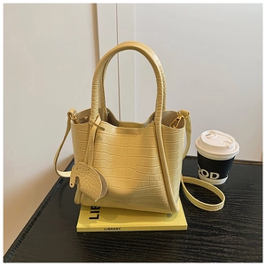 Detail of creamy yellow bucket bag featuring crocodile texture and cute elephant charm