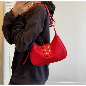 Détail du sac d'épaule en cuir grainé rouge avec boucle argentée en U porté par un mannequin
