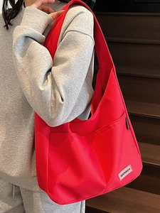 Large capacity red canvas tote bag with shoulder strap shown on model over grey hoodie