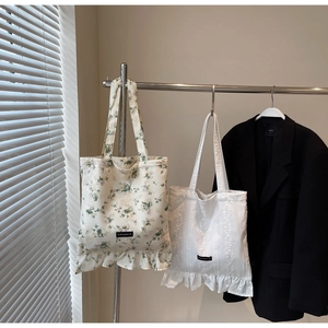 Détail des sacs cabas en toile à fleurs et blanc avec d'élégantes bordures à volants