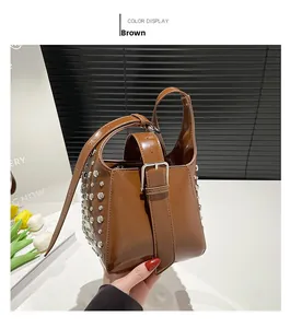 Détail d'un sac seau en cuir marron brillant orné de clous métalliques argentés
