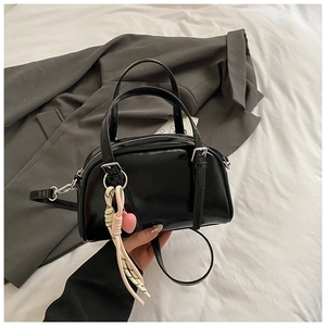 Détail du sac à main noir brillant avec breloque cœur et bandoulière amovible
