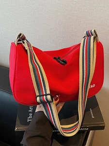 Red canvas dumpling crossbody bag with striped wide shoulder strap and double zip top
