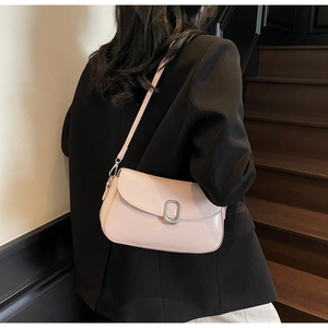 Detail of light pink shoulder bag with silver oval buckle shown on a black blazer