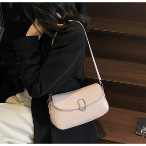 Detail view of pink underarm bag featuring a metallic oval buckle on the leather flap
