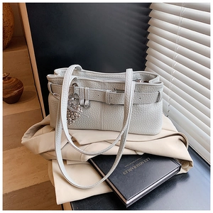 Detail of grey lychee leather texture with buckle strap and silver bead tassel pendant