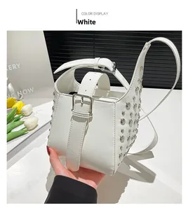 Détail du sac seau blanc avec des clous argentés et une bandoulière en cuir ajustable
