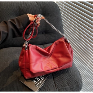 Close-up of red leather handbag featuring textured pleats and silver chain hardware details