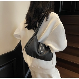 Gros plan du sac à bandoulière en cuir noir grainé avec boucle en métal argenté minimaliste