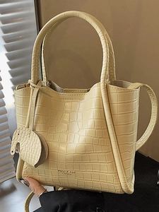 Chic beige bucket bag with crocodile texture, top handle, and cute elephant charm