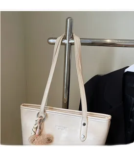 Detailed shot of beige faux leather tote bag with brand lettering and bear charm hanging