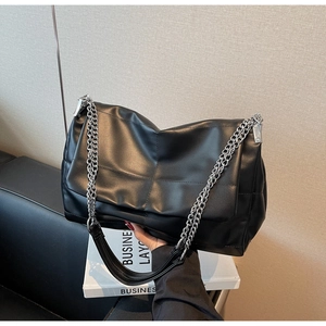 Detail of black quilted leather shoulder bag with silver chain strap and soft texture