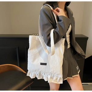 Vue détaillée du sac cabas en toile blanche avec broderie dentelle et bords à volants
