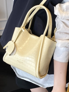 Chic beige crocodile texture bucket bag with a cute elephant charm and shoulder strap