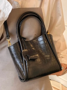 Elegant black crocodile pattern bucket bag with gold hardware shown with a stylish outfit