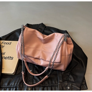 Detail of light pink quilted tote bag with silver chain strap on a black leather jacket