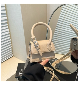 Gros plan sur un sac beige en cuir grainé avec poignée ronde et boucle en métal argenté