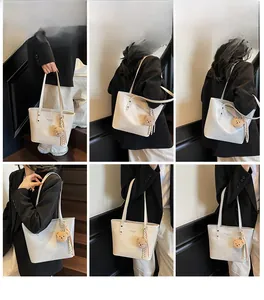 Close-up of minimalist cream tote bag with brown plush bear charm on white stairs