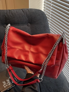 Quilted red PU leather shoulder bag with silver chain strap shown in a natural indoor setting