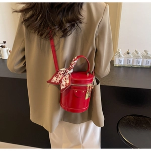 Detail of red leather bucket bag with silk scarf handle on a model in a cafe