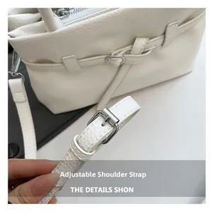 Close-up of the white litchi grain leather bag with adjustable silver buckle strap