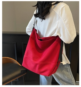 Detailed view of red canvas tote bag with black leather straps worn on shoulder