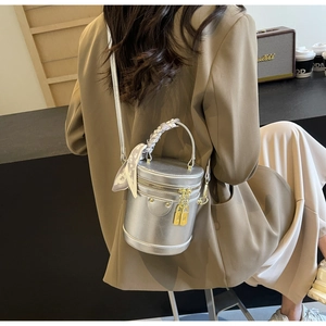 Detail of silver metallic cylinder bag featuring golden locks and silk scarf handle