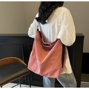 Detail view of large pink washed canvas tote bag with black strap on a shoulder